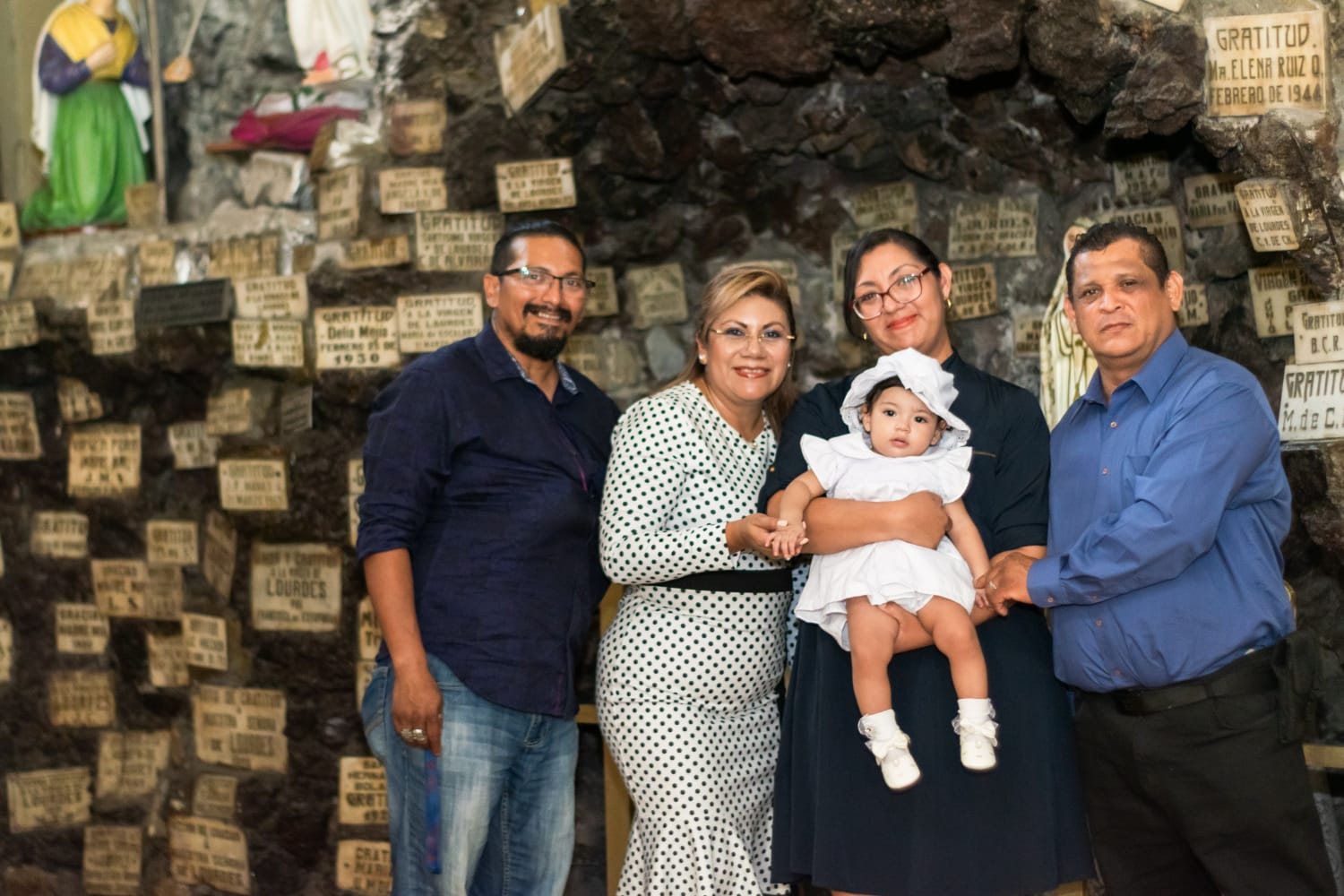 Familia en un bautizo con la bebé vestida de blanco