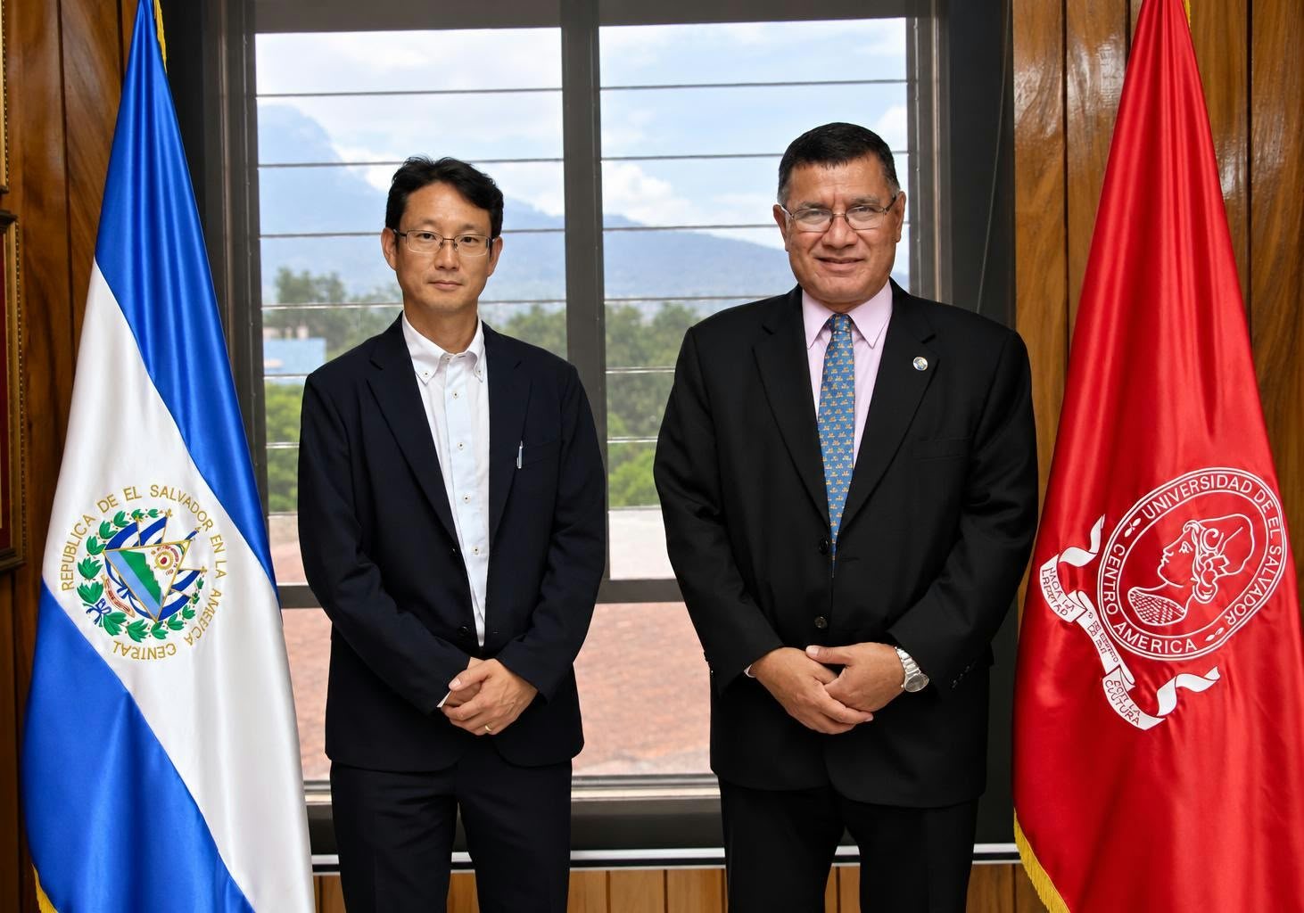 Dos representantes en una reunión institucional junto a banderas